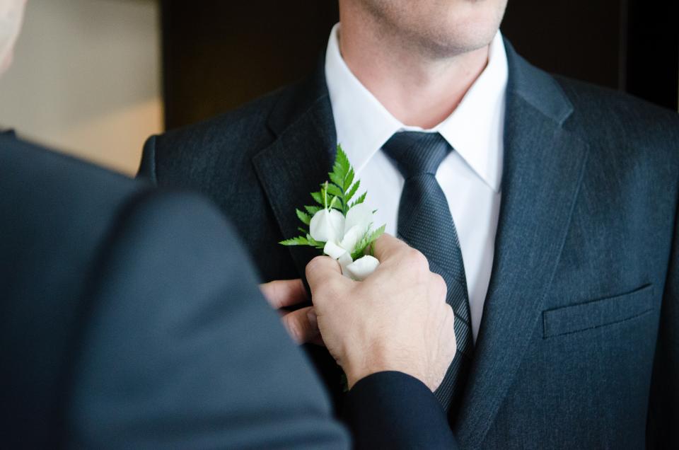 A boutonniere being pinned to a suit jacket
